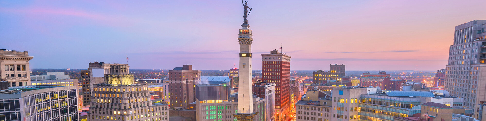 Indianapolis skyline at dusk with the Soldiers and Sailors Monument in downtown traffic circle.